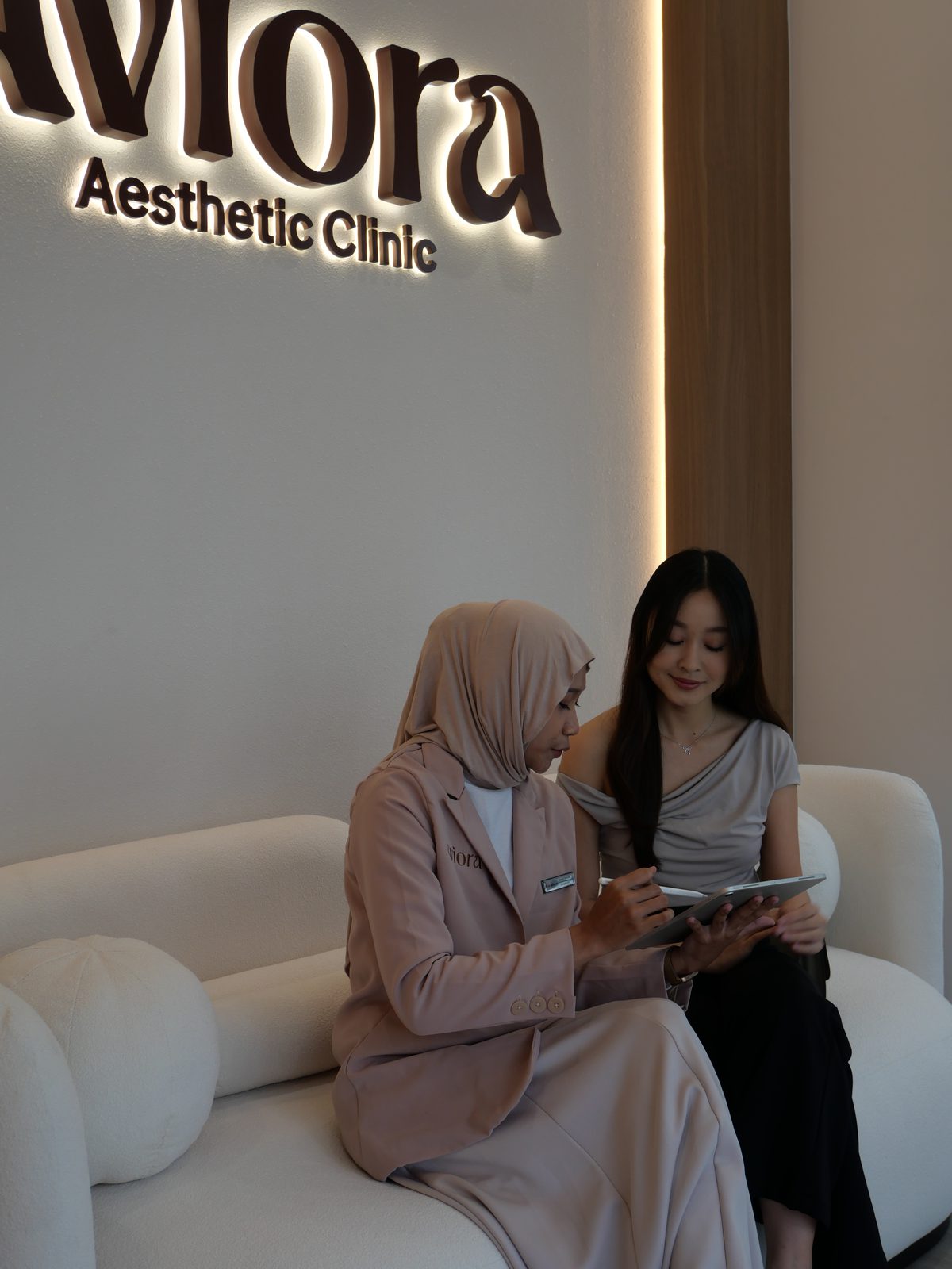 Consultation on the reception sofa beneath the Aviora sign