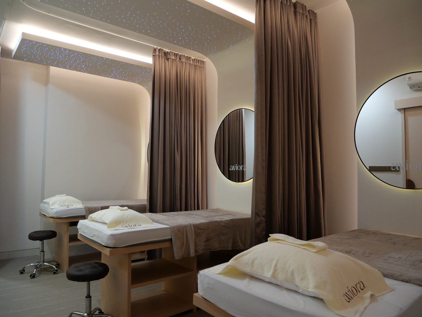 Facial room with a backlit circular mirror and draped curtain