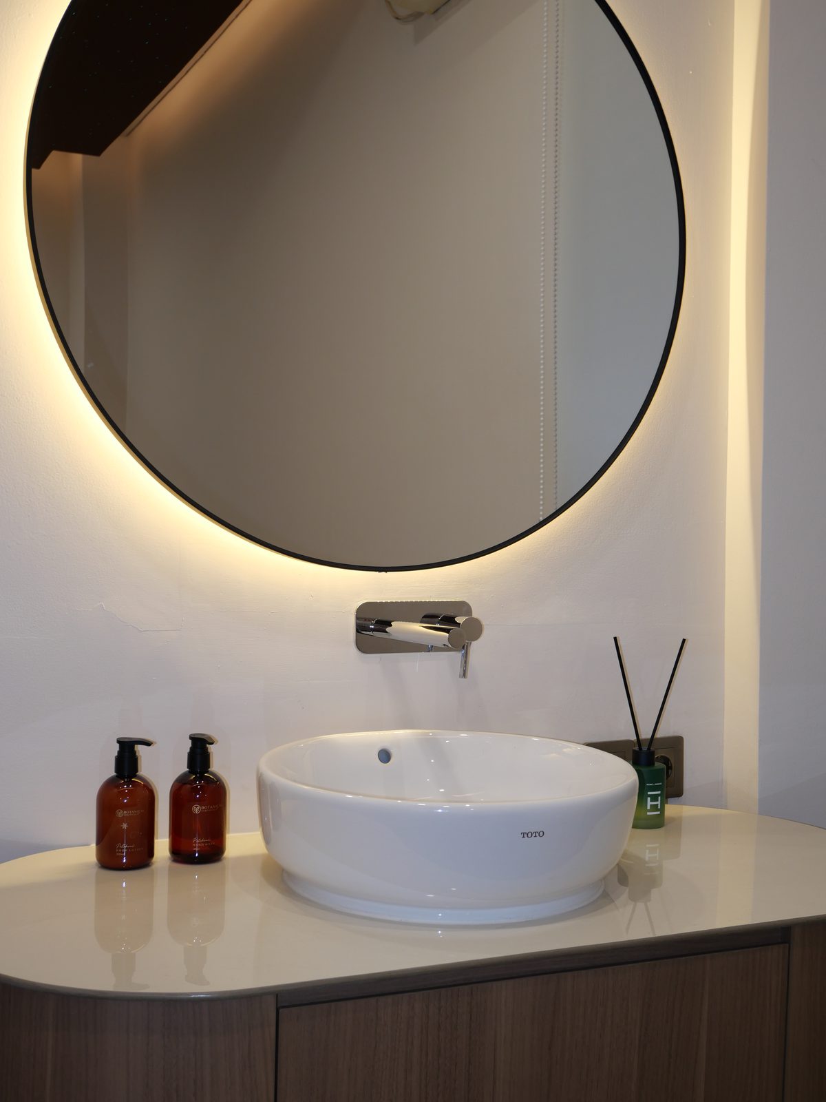 Vanity basin under a circular backlit mirror
