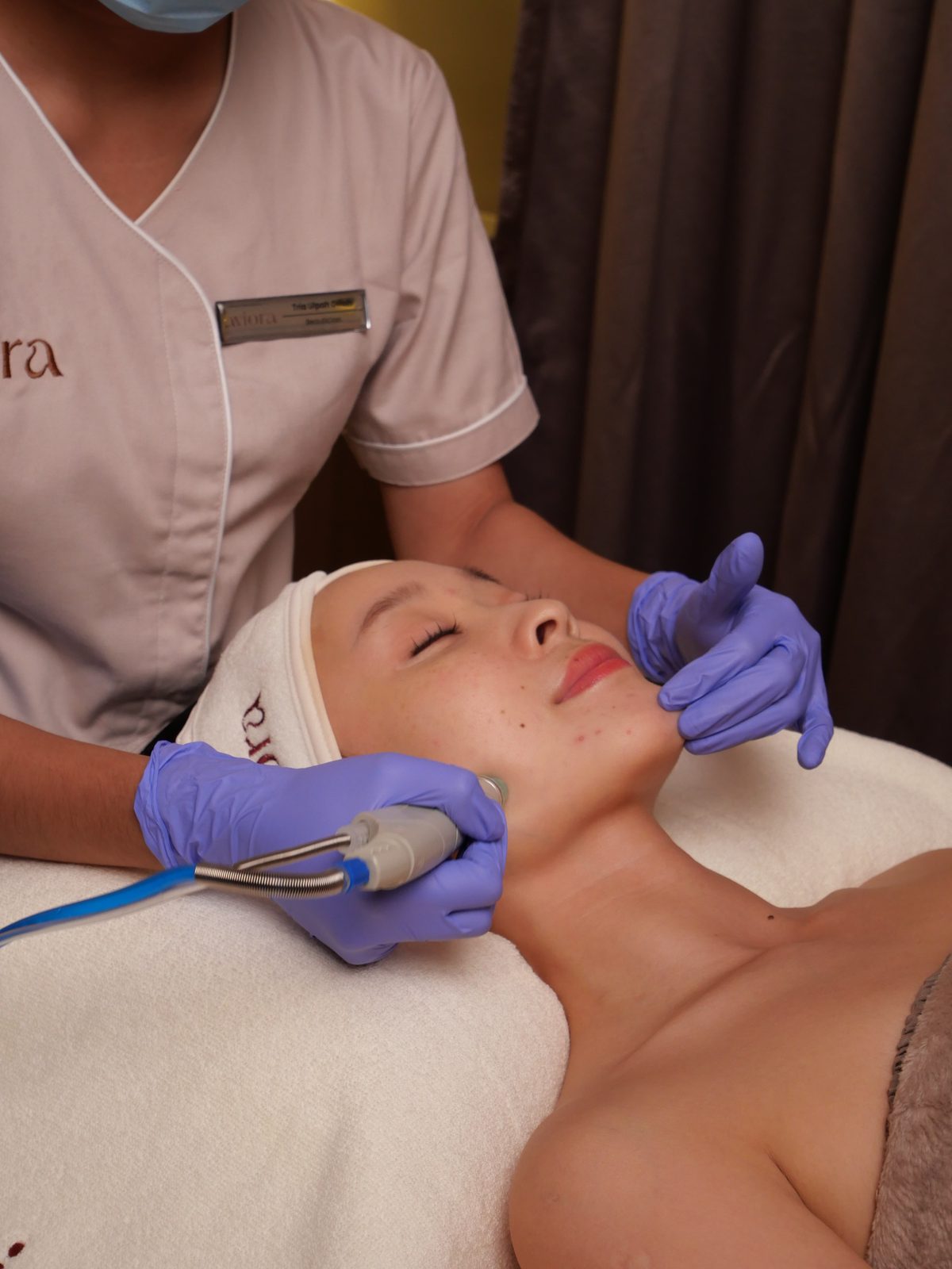 Aesthetician guiding a treatment handpiece along the jawline